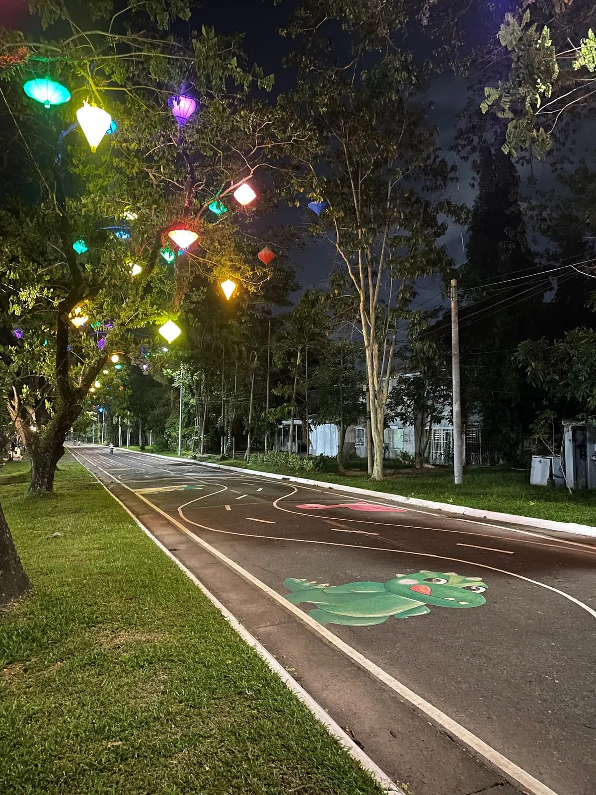 Ağaçlara asılmış renkli fenerlerle aydınlatılmış gece yürüyüş yolu
