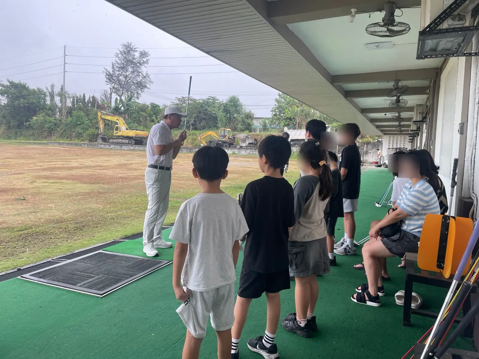 Certified teaching pro giving a group golf lesson to Talk Academy students