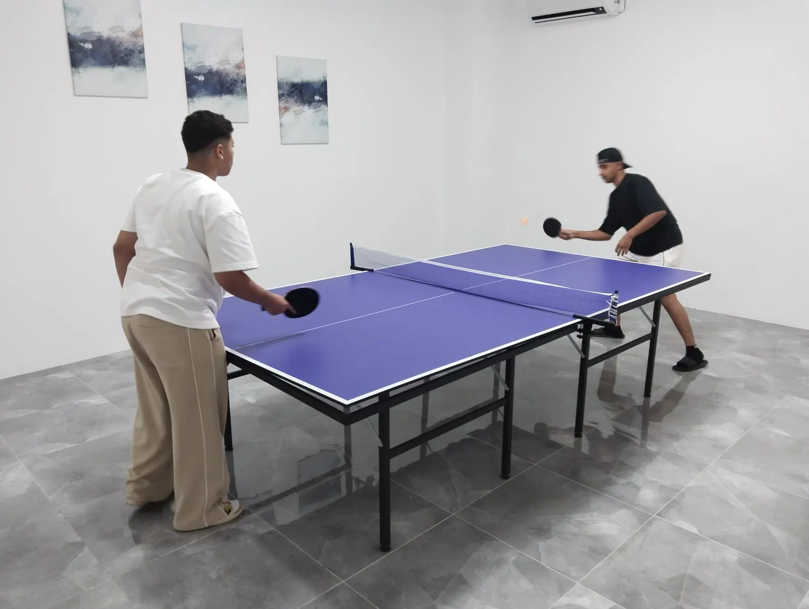 Two students playing table tennis in the activity room
