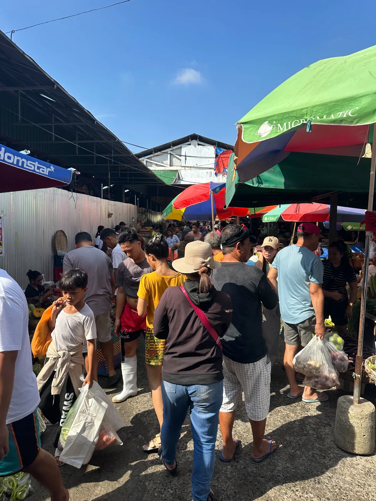 ตลาดพื้นบ้านใกล้โรงเรียน ผู้คนจับจ่ายใต้ร่ม