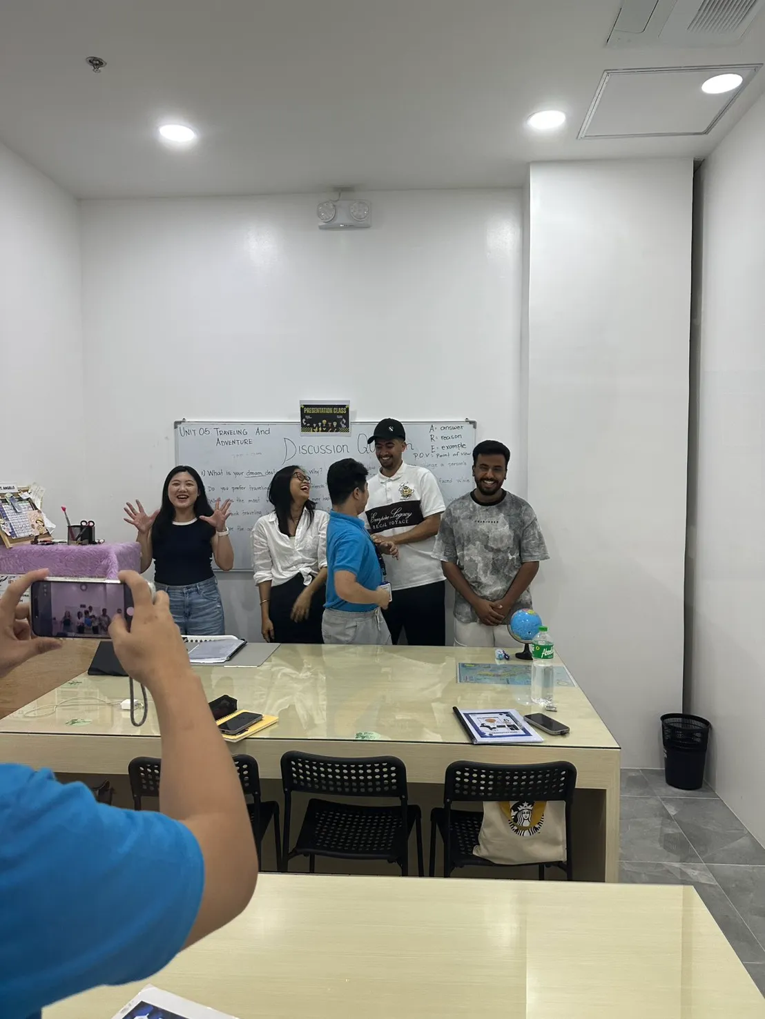นักเรียนยืนด้วยกันหลังพรีเซนต์ในคลาสกลุ่ม บนกระดานด้านหลังเขียนว่า Discussion