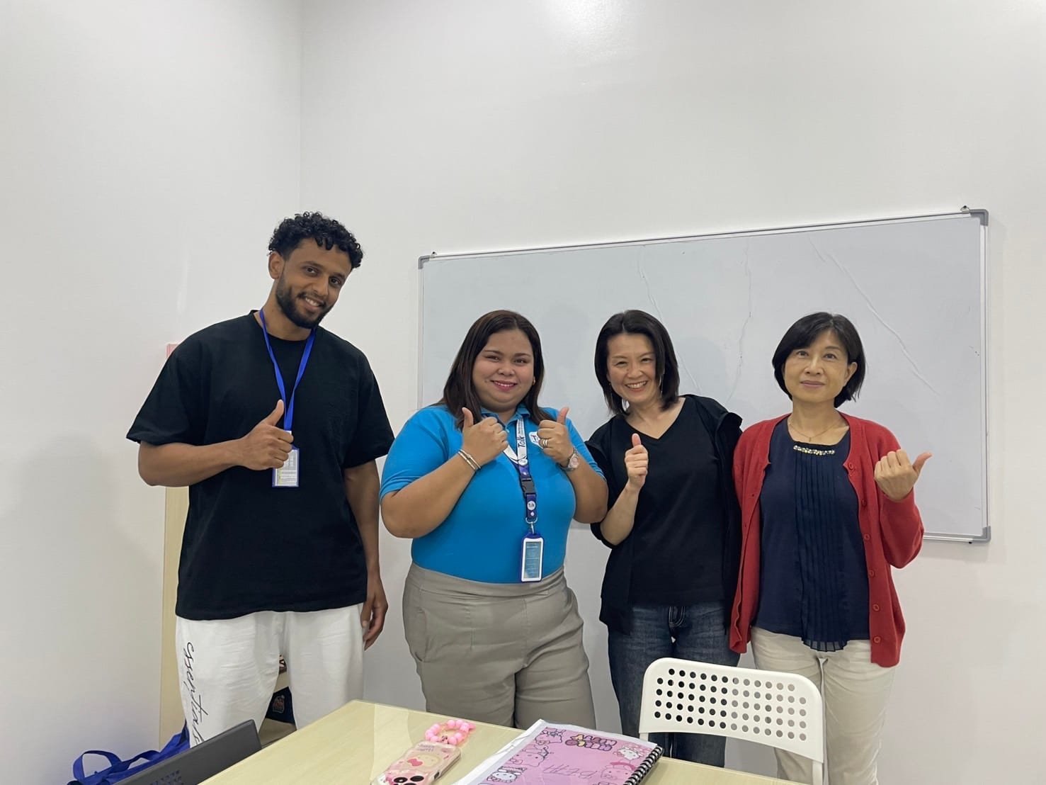 Momoe standing with a Saudi student, local staff and classmates in front of a classroom whiteboard