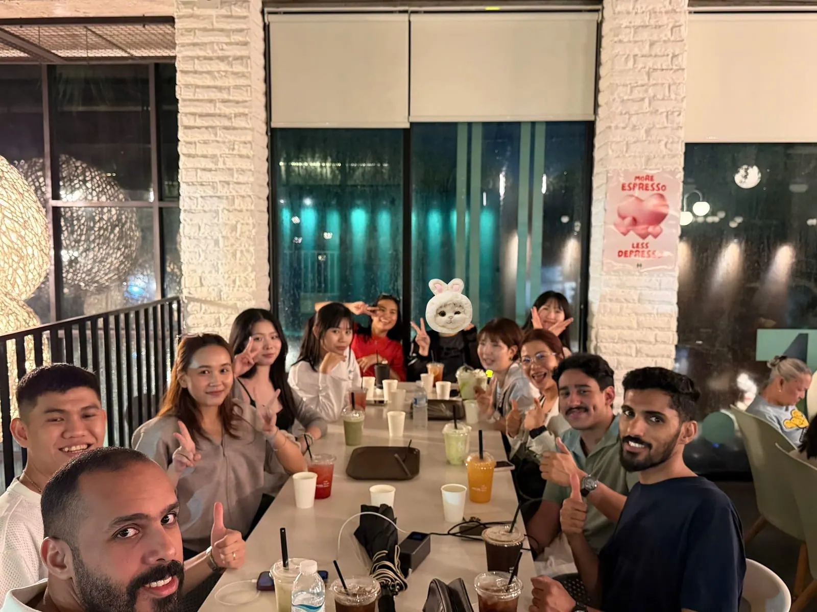 Estudantes de várias nacionalidades em volta de uma mesa comprida num café à noite