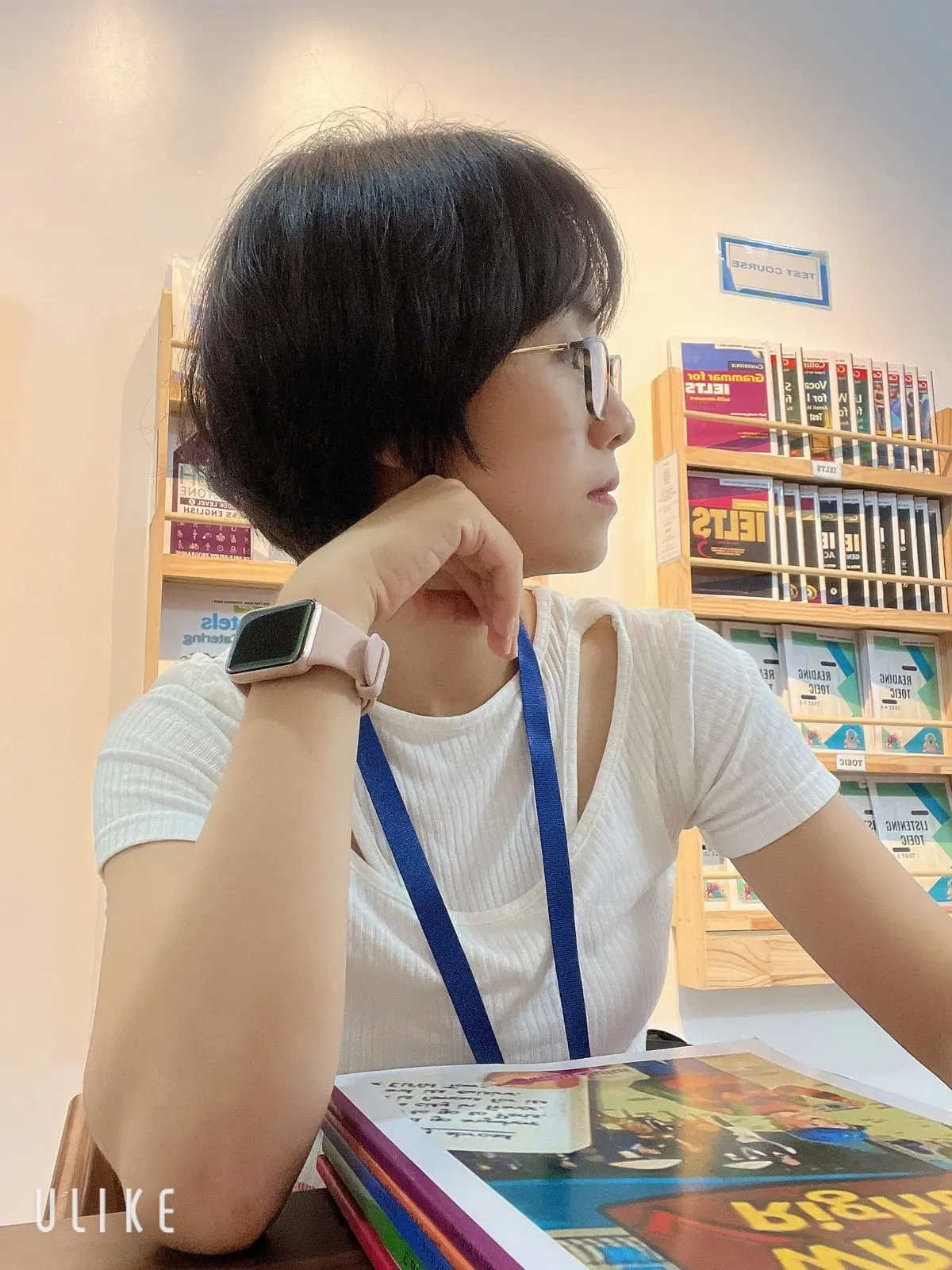 Thu Hanh studying alone beside the test-prep bookshelves