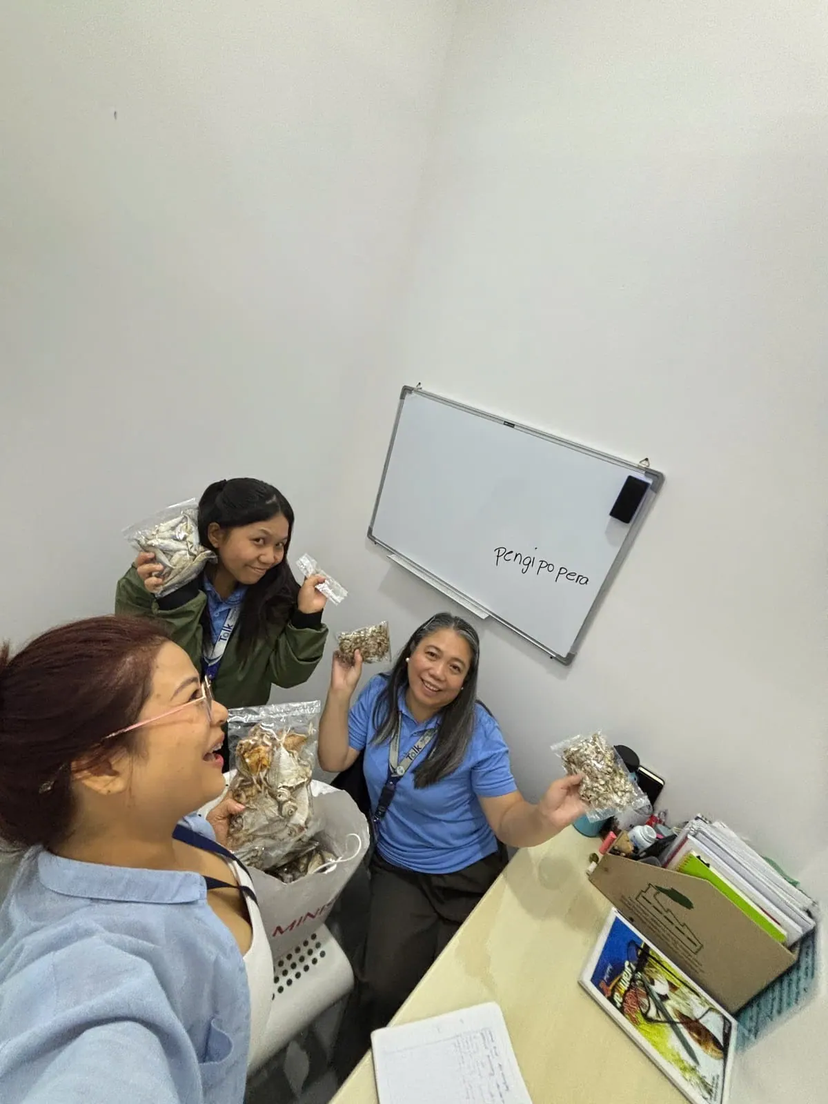 Thu Thao holding local snacks with school staff in the office